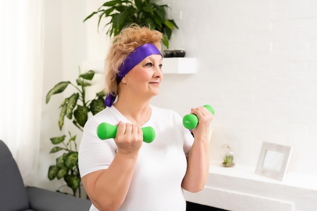 Senior woman doing physical exercises with a dumbbell.