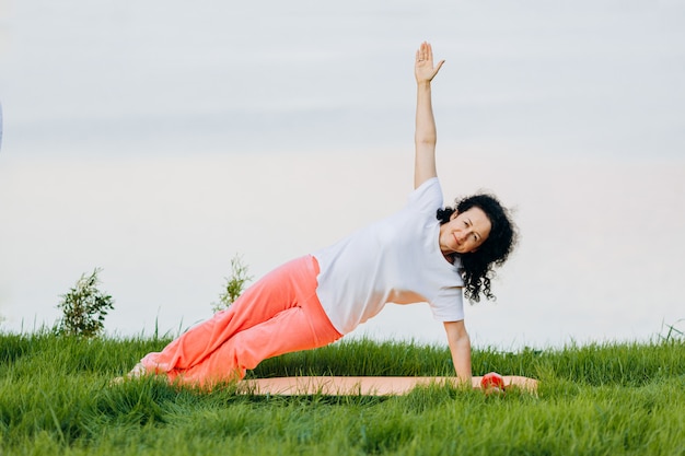 Senior  woman doing yoga asana side plank  outdoor. .  yoga 