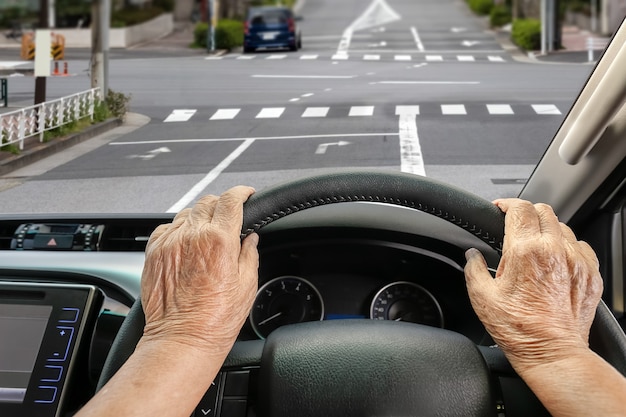 Senior woman driving a car on street in city.