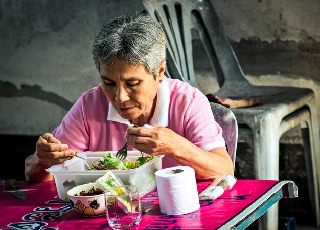 Senior woman eating while sitting on chair