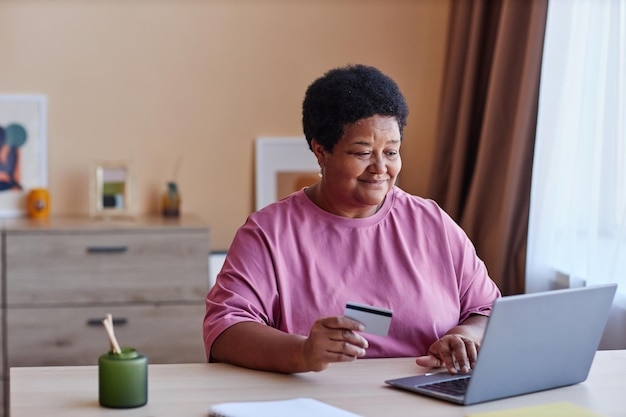 Senior woman entering data of her credit card while ordering online products