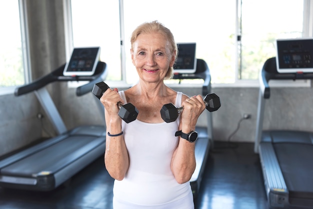 Senior woman exercise lifting dumbbell in fitness gym.