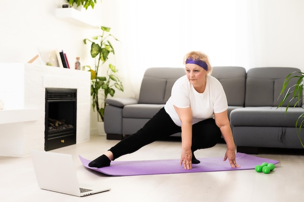 Senior woman exercise using laptop online instructions at home health care.