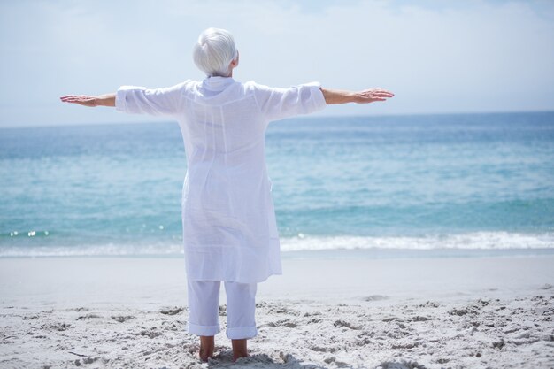 Senior woman exercising at sea shore on sunny day