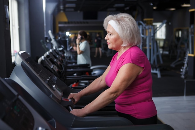 Senior donna che si esercita su un tapis roulant in palestra