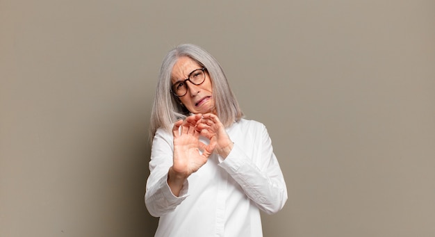 Senior woman feeling disgusted and nauseous, backing away from something nasty, smelly or stinky, saying yuck