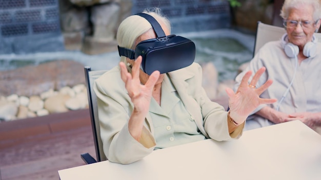 Photo senior woman gesturing while using virtual reality goggle in geriatric