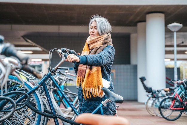 年配の女性が駐車場で自転車を手に入れる