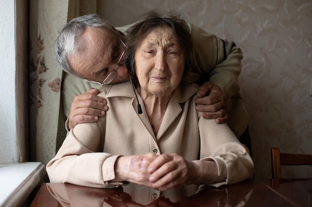 Senior woman gets a kiss from her loving adult son who has come to visit her in the nursing home.