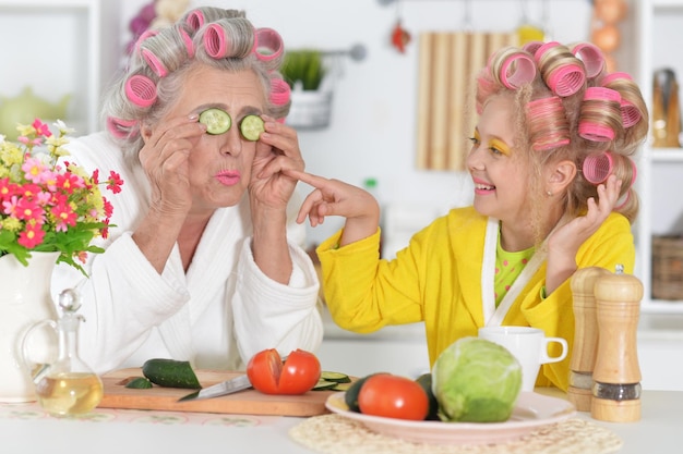 Senior woman and girl with pink hair curlers on head