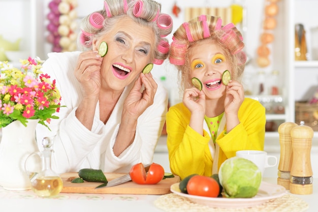 Senior woman and granddaughter at kitchen with  vegetables