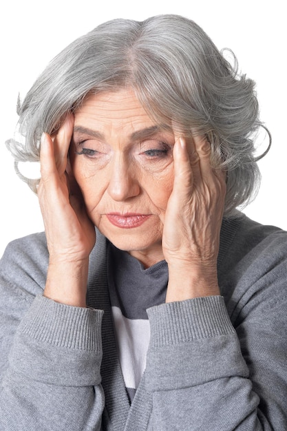 Senior woman in grey blouse with headache isolated on white background