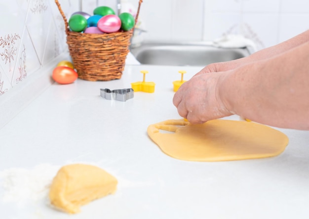 Senior woman hands cut out from dough pastry cookies for Easter day Happy Easter concept Process of making cookies Cooking at home concept Tradition homemade food