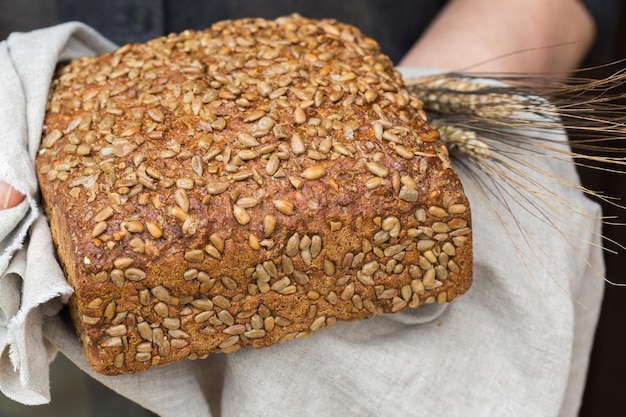 Senior woman hands holding freshly baked loaf of rye bread