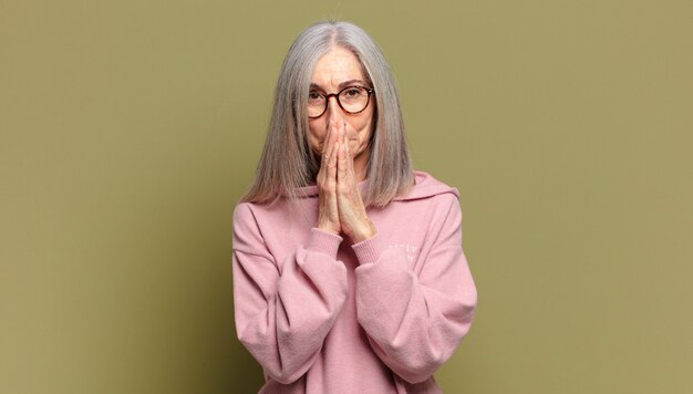 Senior woman happy and excited, surprised and amazed covering mouth with hands, giggling with a cute expression