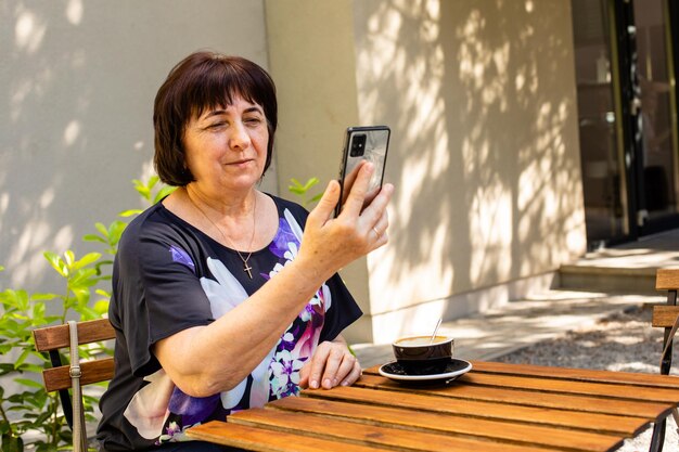 The senior woman have video chat with friends in a cafe