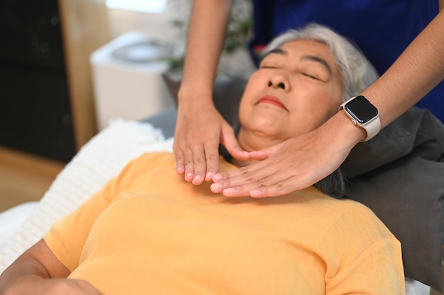 치료사와 함께 레이키 치유 치료를 받는 노인 여성 대안 의학 및 레이키 기술 개념