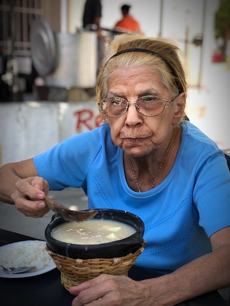 Photo senior woman having soup while sitting at table