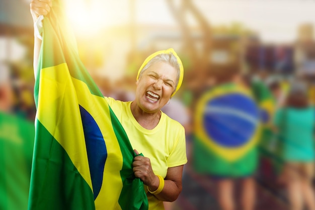 Senior woman holding brazil flag on cinematic background written towards hex in portuguese