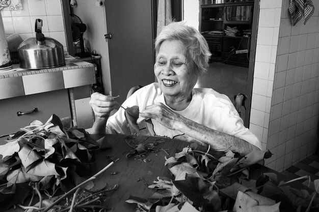 Photo senior woman holding dried leaf at table