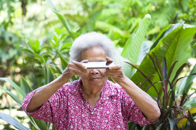 Senior woman holding mobile phone in front of eyes