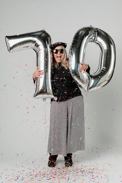 Senior woman holding silver balloons for 10 years celebration