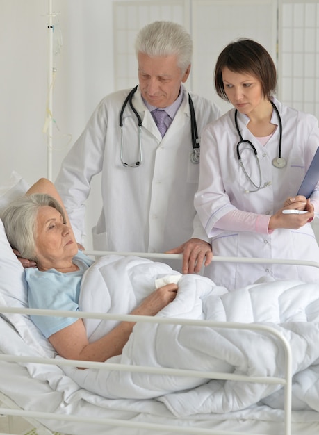 Senior woman in hospital with caring doctors