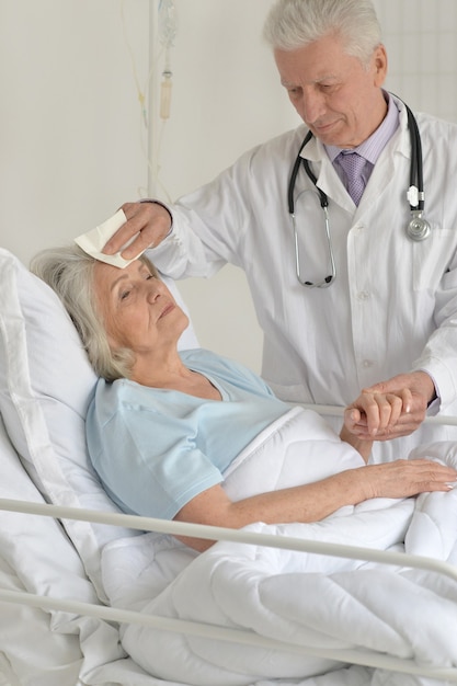 Senior woman in hospital with caring doctors