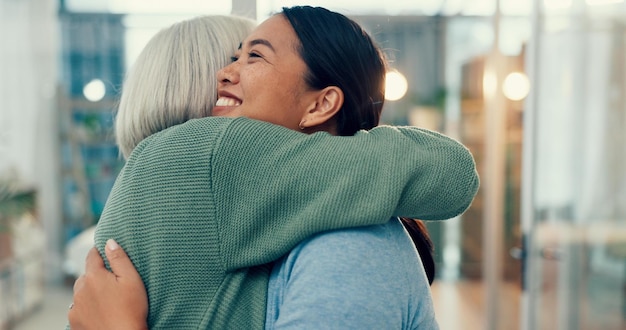 Photo senior woman hug and old friend at a business office with a smile support and excited elderly person love and happy women together at a workplace with care from staff at physiotherapy with health