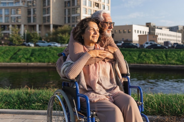 写真 車椅子に乗った高齢の女性が介護者と歩いている公園の道路に乗っている高齢の男性高齢の夫婦