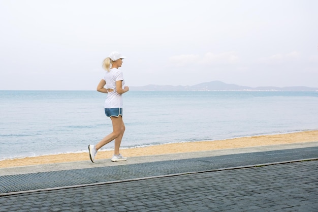 Donna anziana che fa jogging lungo un lungomare all'aperto copia spazio stile di vita sano