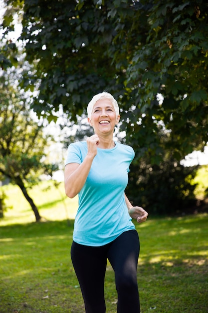 Senior woman jogging through park