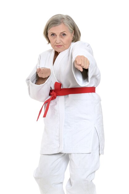 Senior woman in karate pose on white background