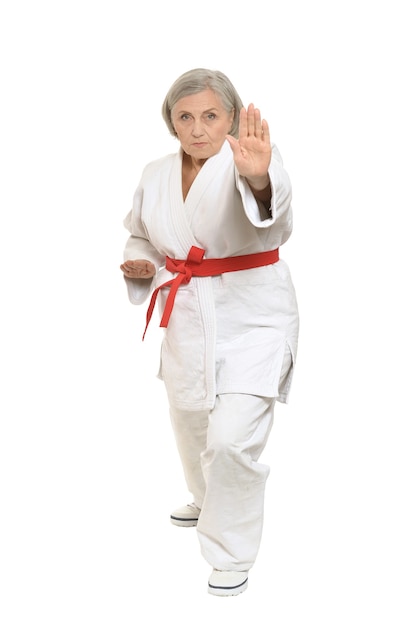 Senior woman in karate pose on white background
