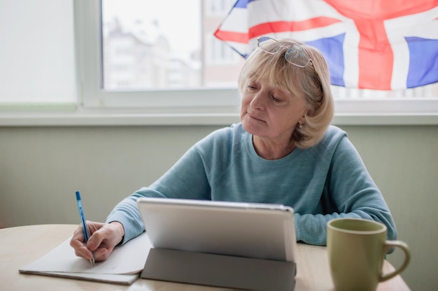 Senior woman learns english via internet with laptop language classes for ukrainian refugee