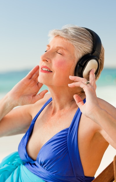 ビーチで音楽を聴いているシニアの女性