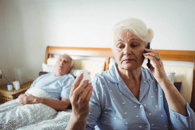 薬瓶を見て、電話で話している年配の女性