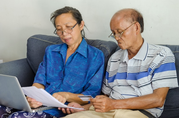 Senior woman and man looking business documents computer and credit card