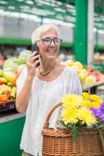 Senior woman on market using mobile phone