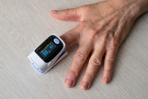 Senior woman measure oxygen saturation with pulse oximeter machine and result show normal value at the hospital clinic. healthcare and medical concept