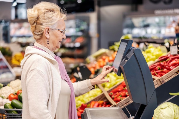 슈퍼마켓에서 규모로 제품을 측정하는 노인 여성