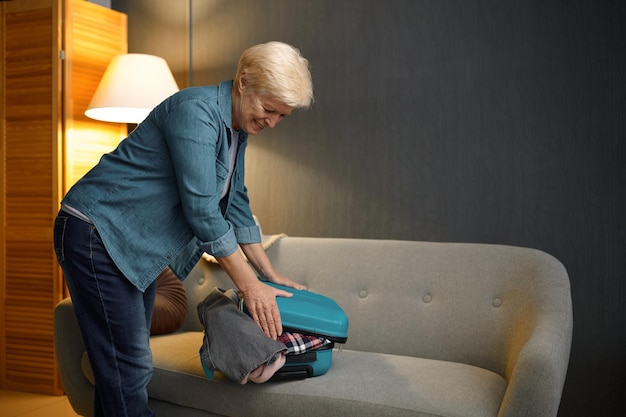 Senior woman packing luggage for new journey