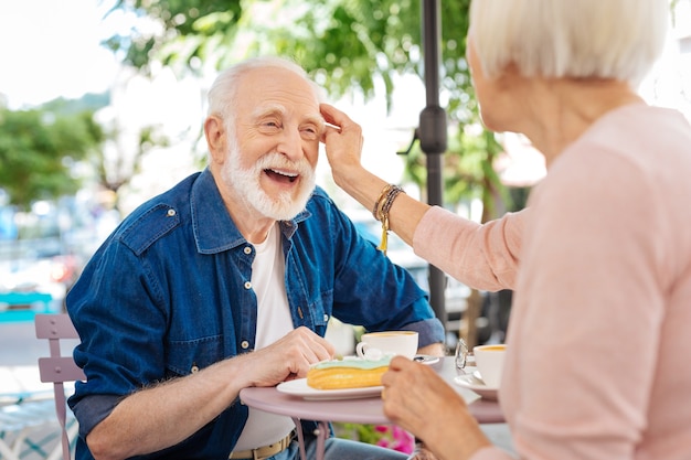 Senior woman palming jovial husband who laughing