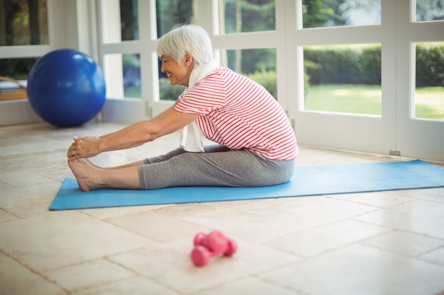 Photo senior woman performing stretching exercise at home