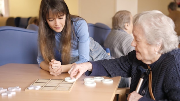 Photo senior woman playing board game with a woman