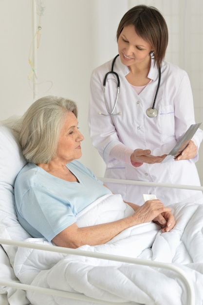 Senior woman portrait in hospital with caring doctor