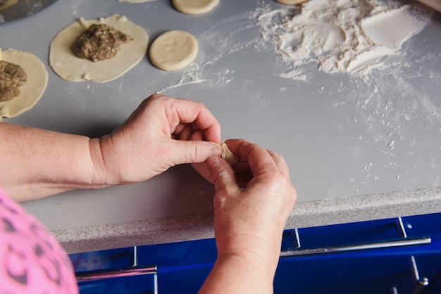 Senior woman prepares khinkali.