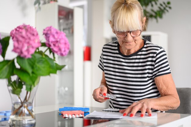 Senior woman preparing pill box at home
