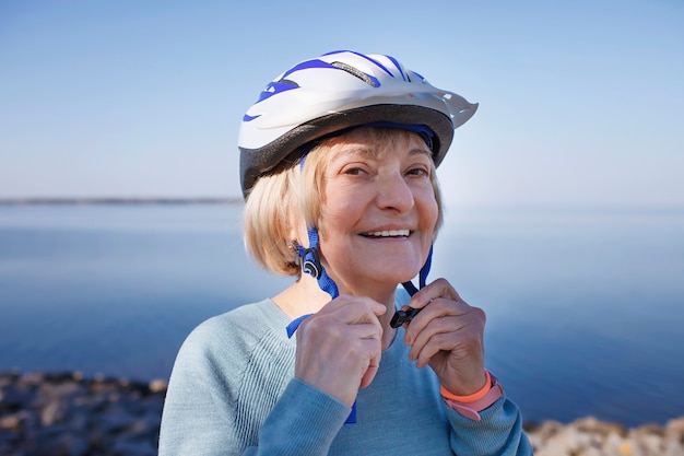 Senior woman puts on safety helmet before roller skating in nature mental and physical health