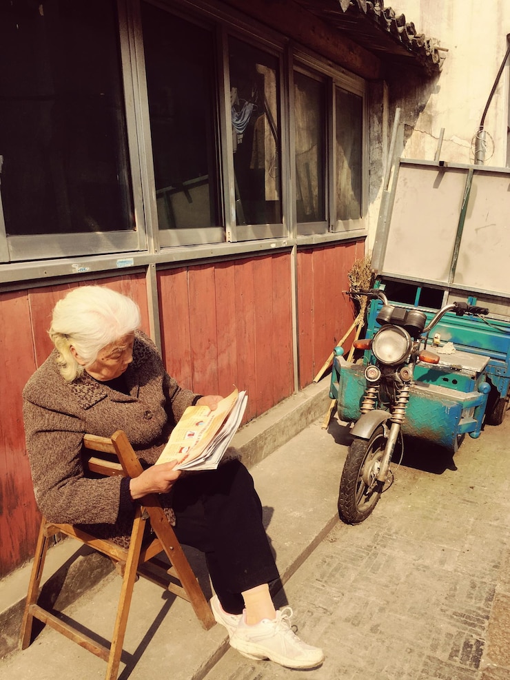 Photo 高齢の女性が歩道で本を読んでいる